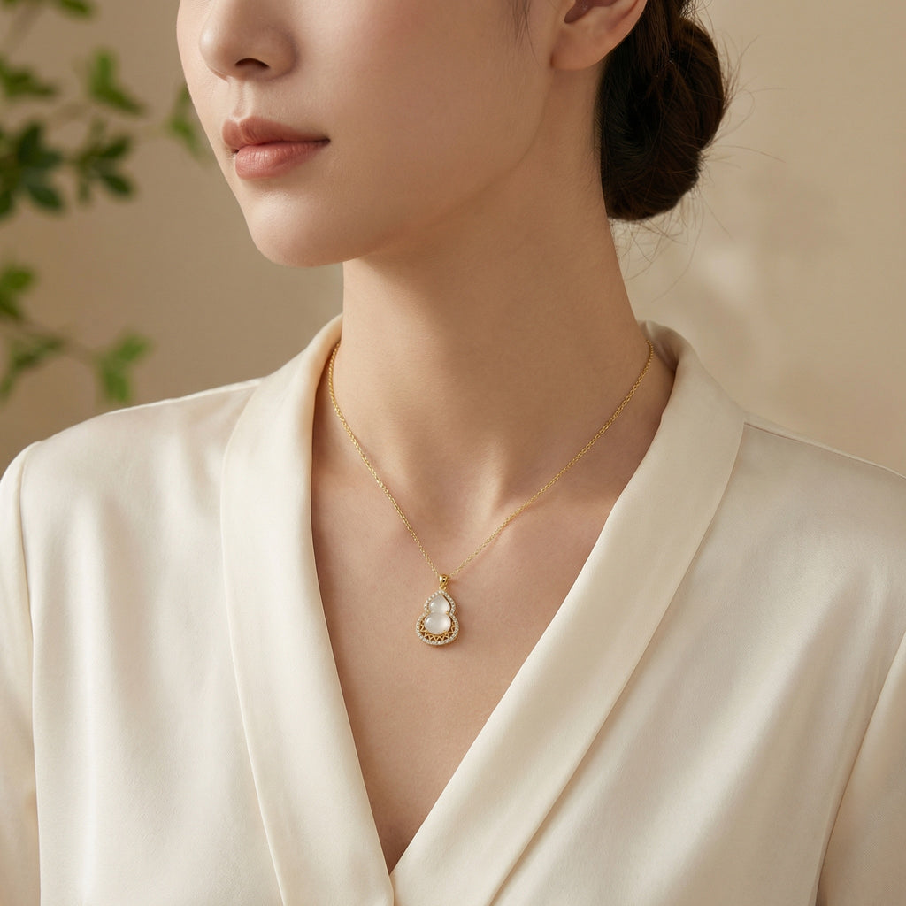 Woman wearing a gold necklace with a pearl pendant against a neutral background