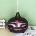 Black and pink essential oil diffuser on a table with a green wall background