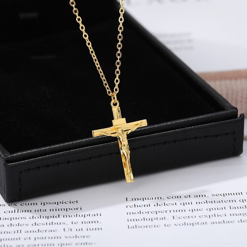 Gold crucifix necklace on a black box with text underneath
