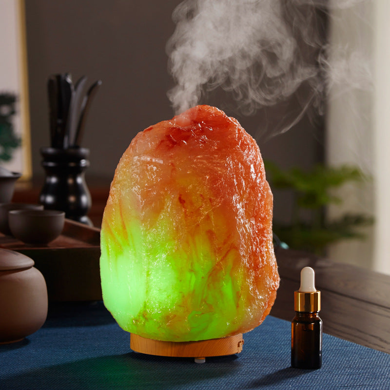 Decorative stone diffuser emitting steam with a dropper bottle on a table.