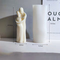 White sculpture of a woman holding a child with dimensions displayed on a gray background