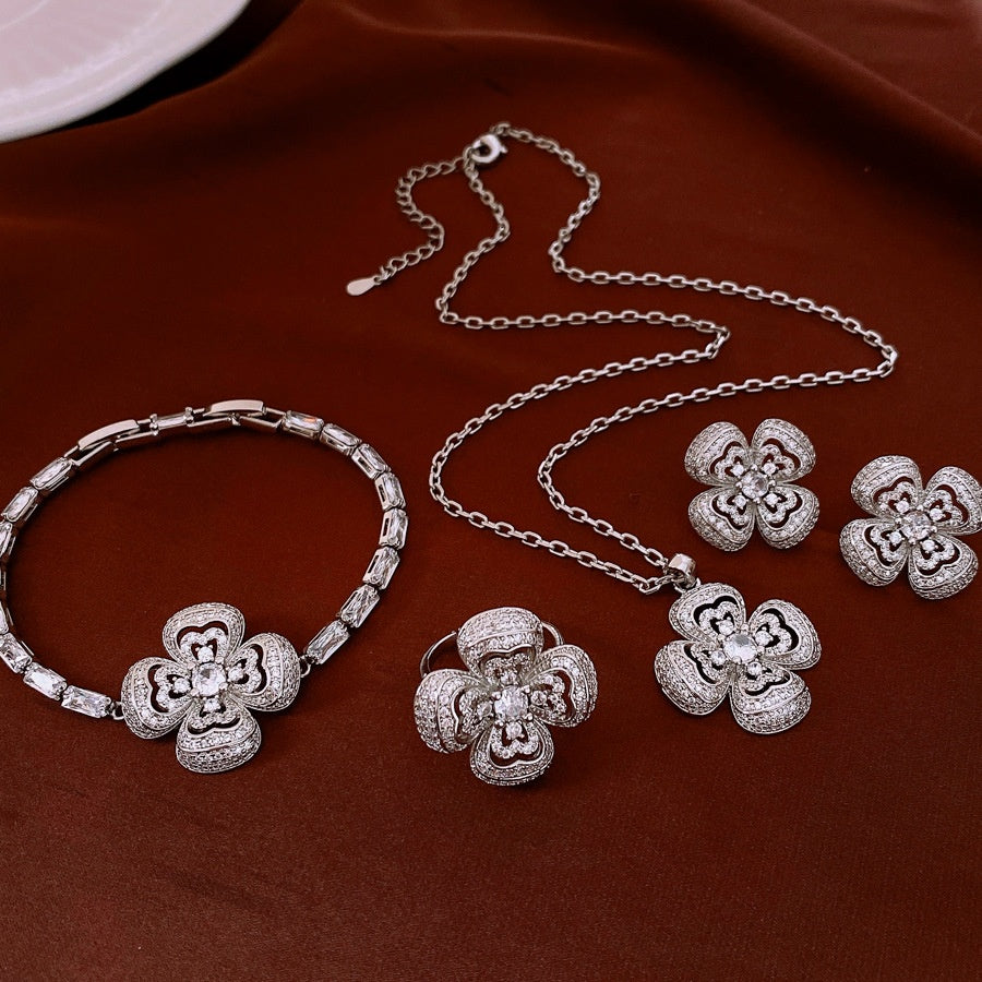 Silver jewelry set with floral designs on a brown surface