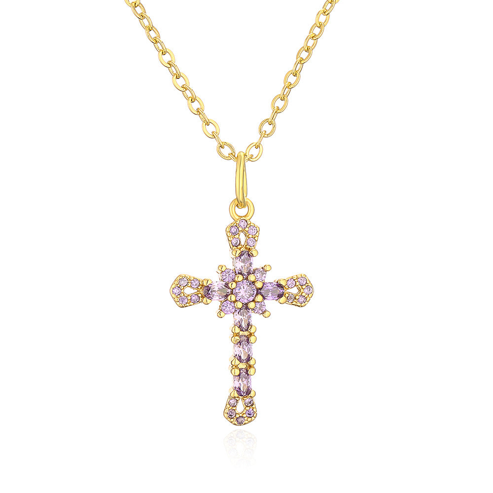 Gold cross necklace with pink gemstones on a white background
