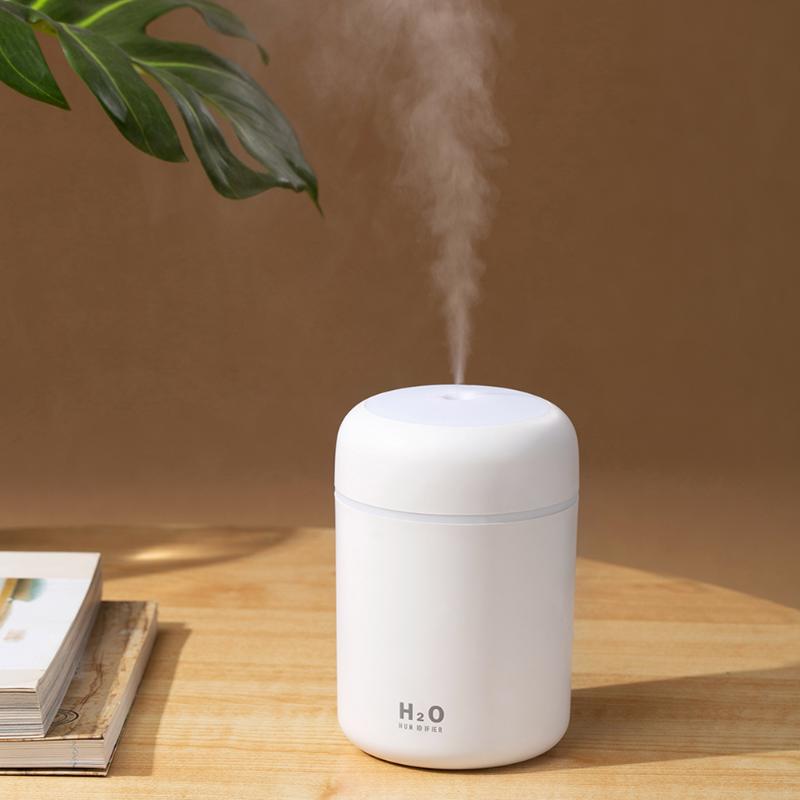 White humidifier emitting steam on a wooden surface with a plant in the background