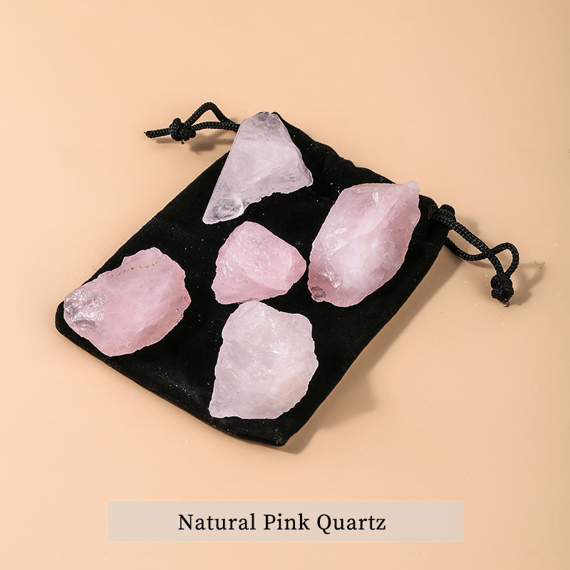 Five natural pink quartz crystals on a black drawstring bag with a beige background.