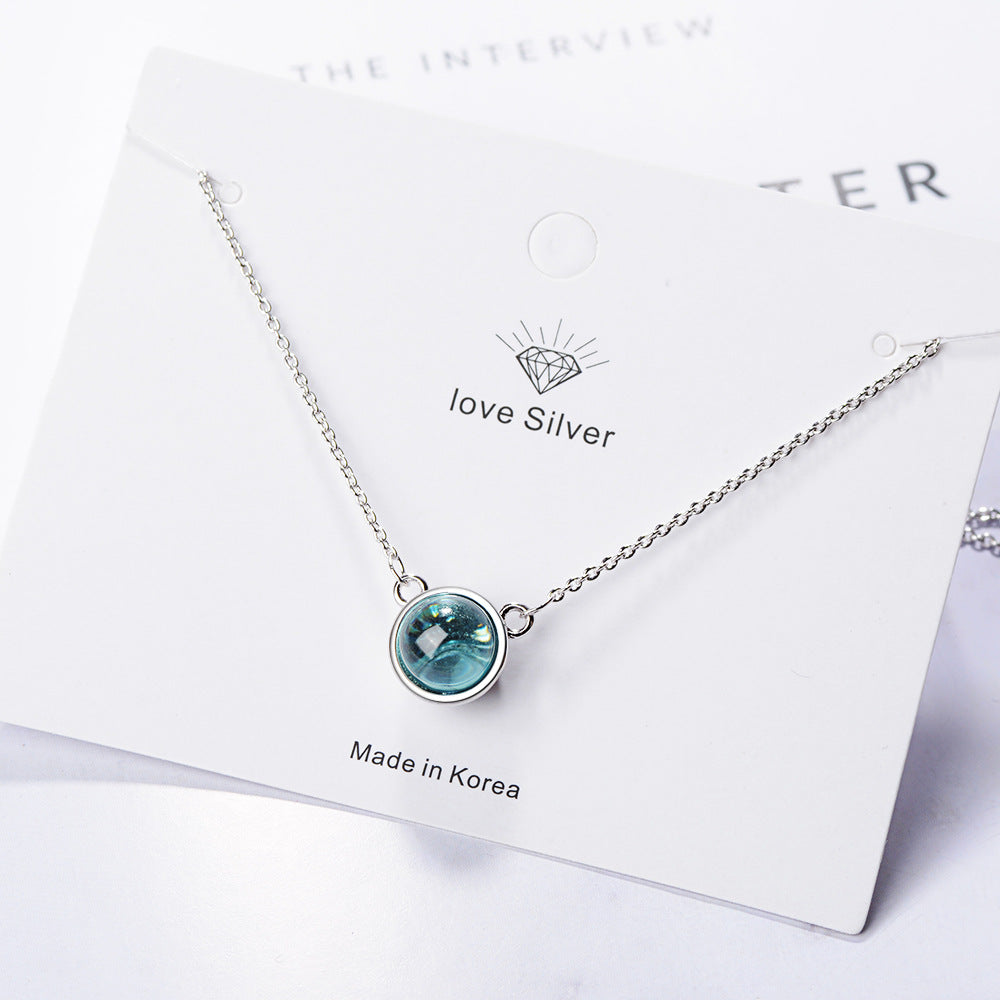 Silver necklace with a green gemstone on a branded card