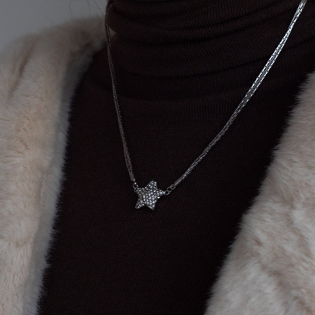 Star-shaped necklace on a black turtleneck against a fur background