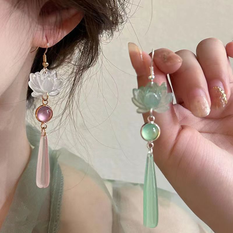 Close-up of a person wearing elegant earrings with floral and teardrop designs.
