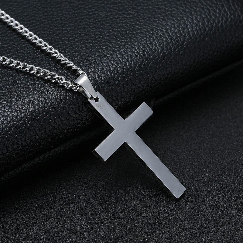 Silver cross pendant necklace on a black leather surface
