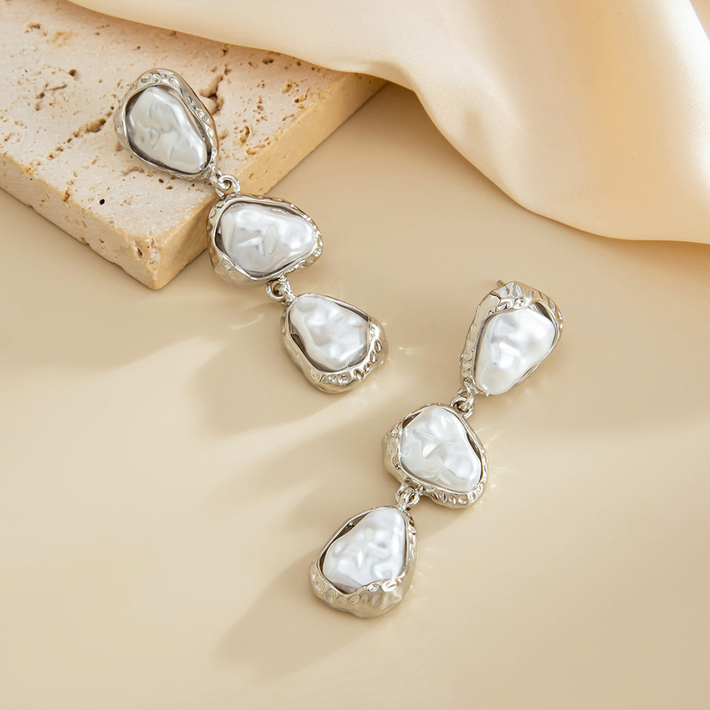 Silver earrings with white stones on a beige surface