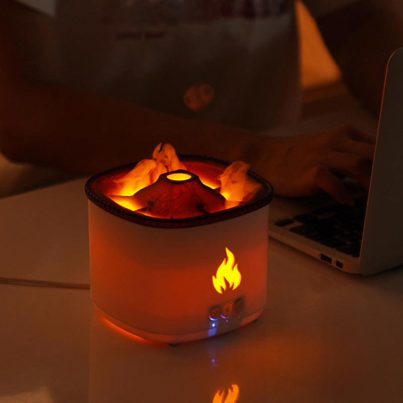 Small fire pit lamp on a desk with a person using a laptop in the background