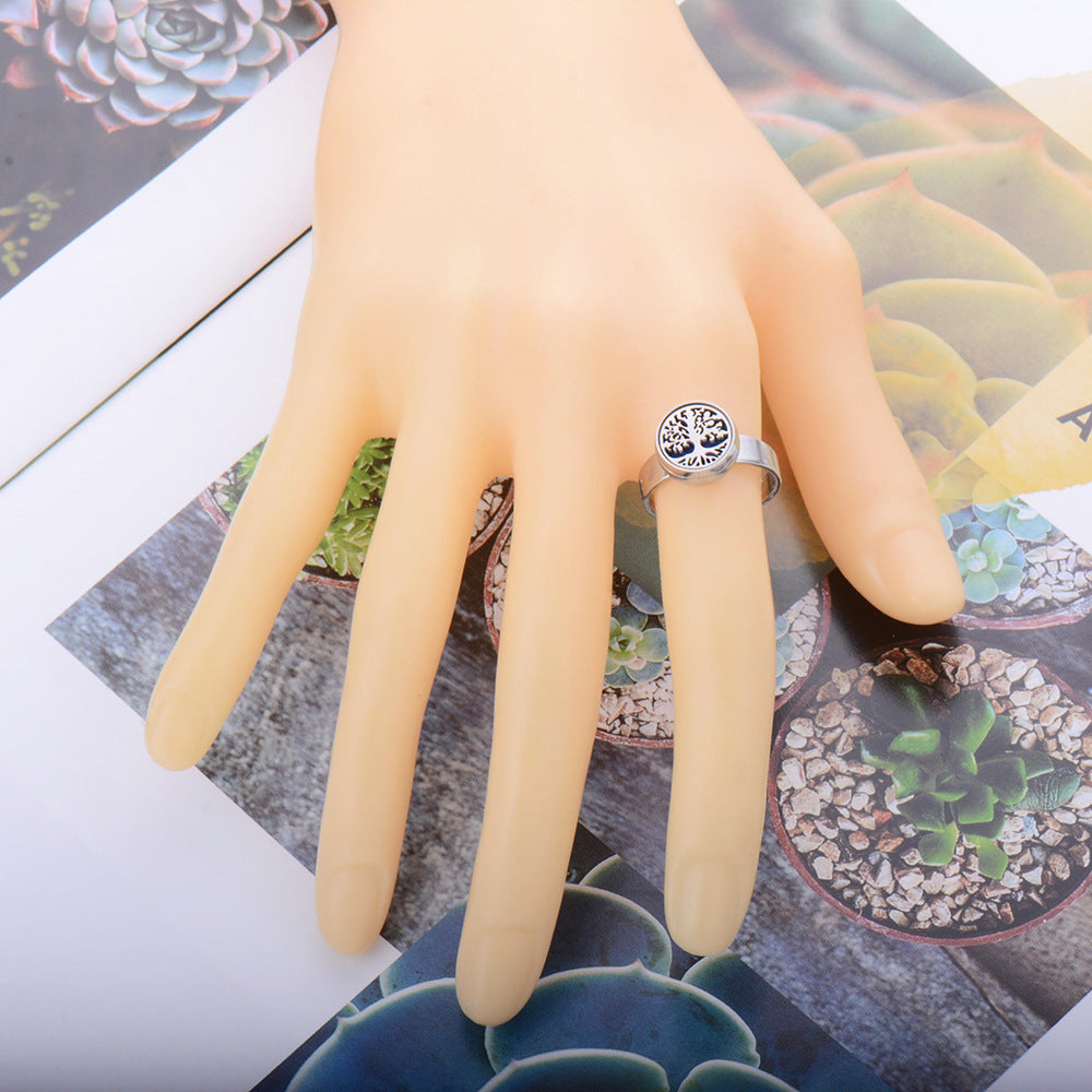 Hand wearing a silver ring with a tree design on a background of succulent plants.