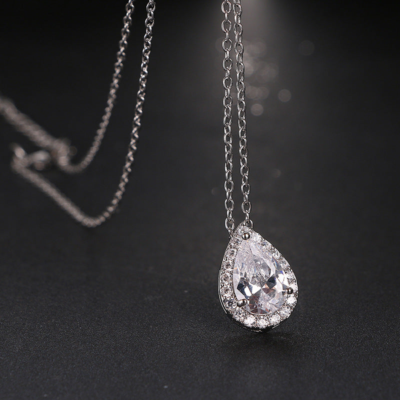 Teardrop-shaped diamond pendant on a chain against a dark background