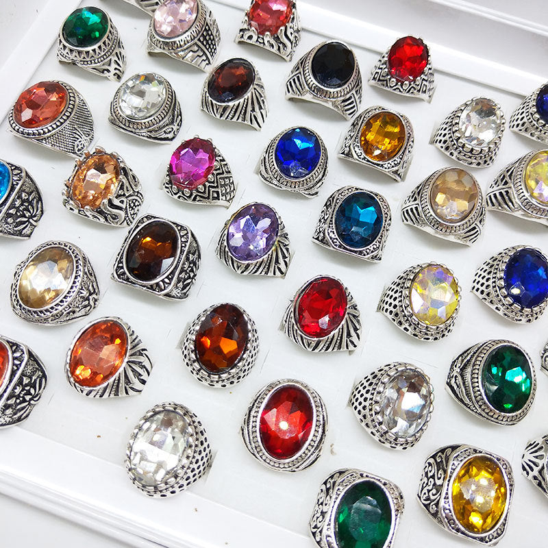 Collection of colorful gemstone rings on a white surface