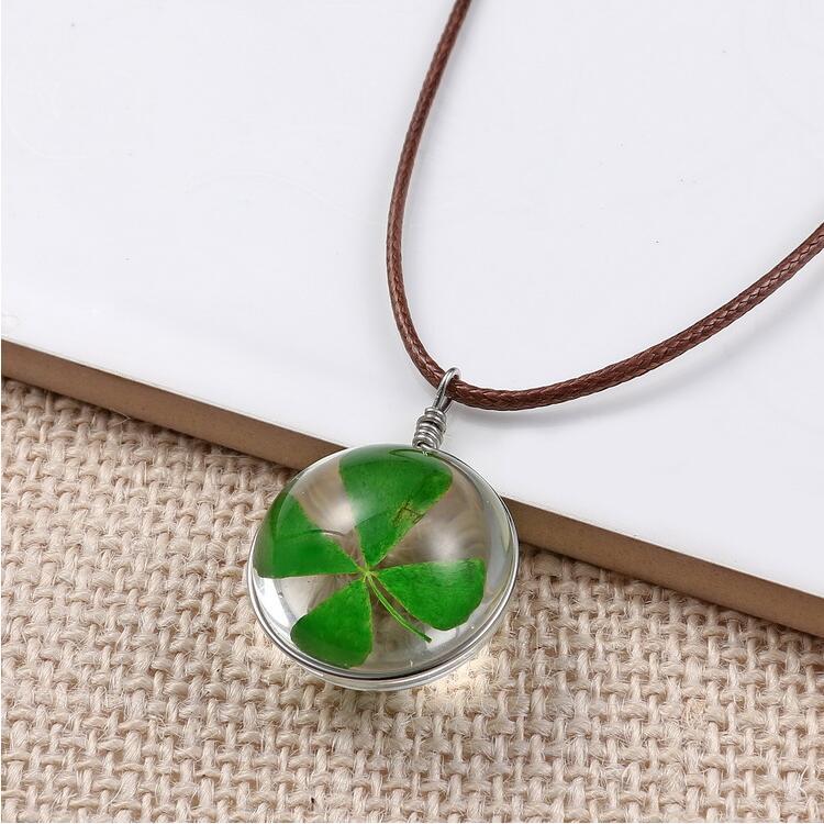 Necklace with a round pendant featuring a four-leaf clover inside, on a textured fabric background.