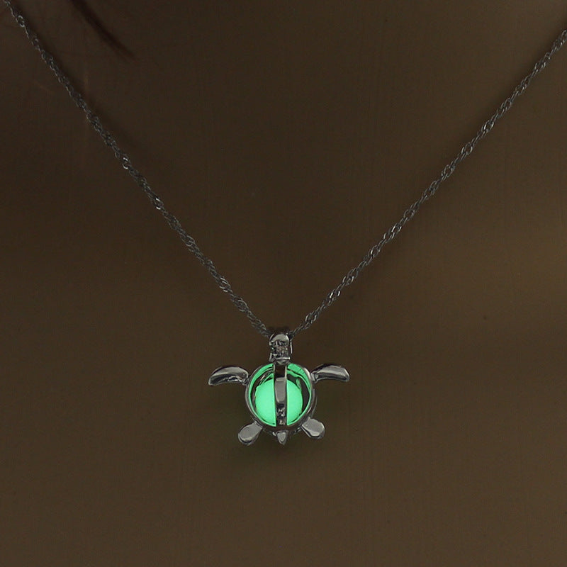 Turtle-shaped pendant with a green glow on a dark chain against a brown background
