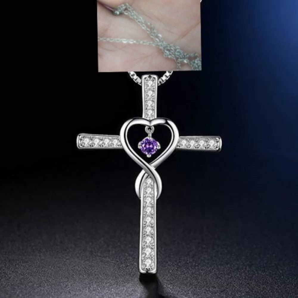 Silver cross pendant with heart design and purple gemstone on a dark background