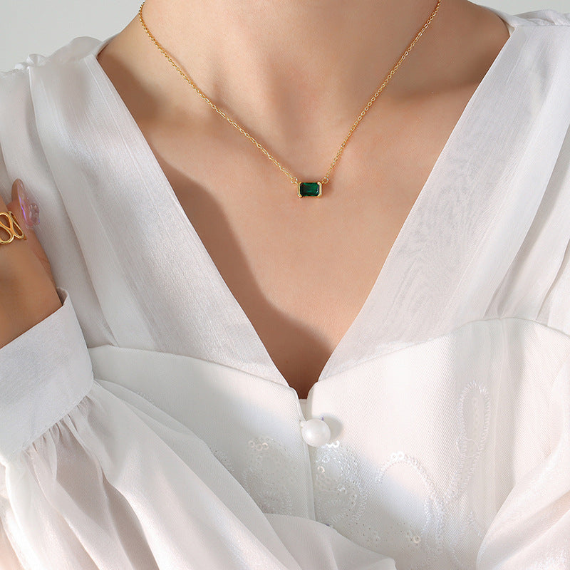 Gold necklace with a green pendant on a white blouse