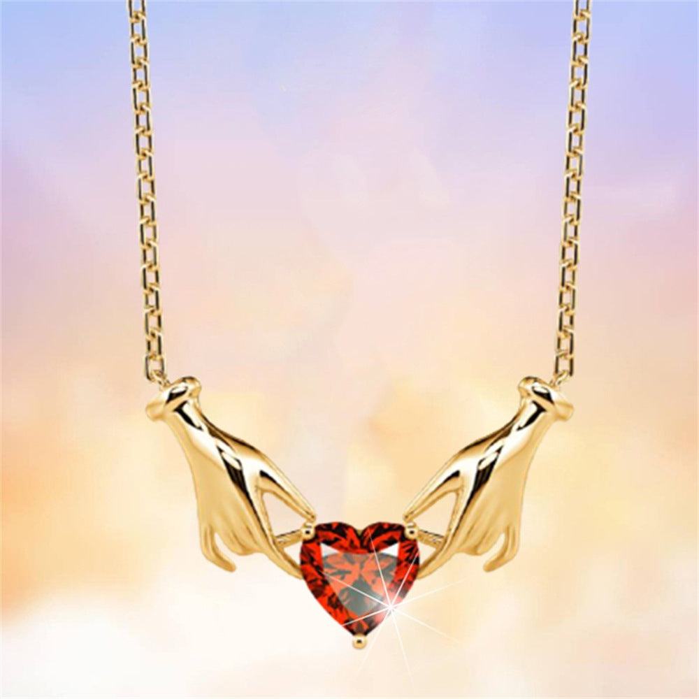 Gold necklace with a red heart-shaped pendant on a gradient background