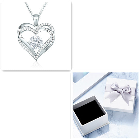 Heart-shaped silver necklace with clear stones on a white background, next to a white box with a bow.