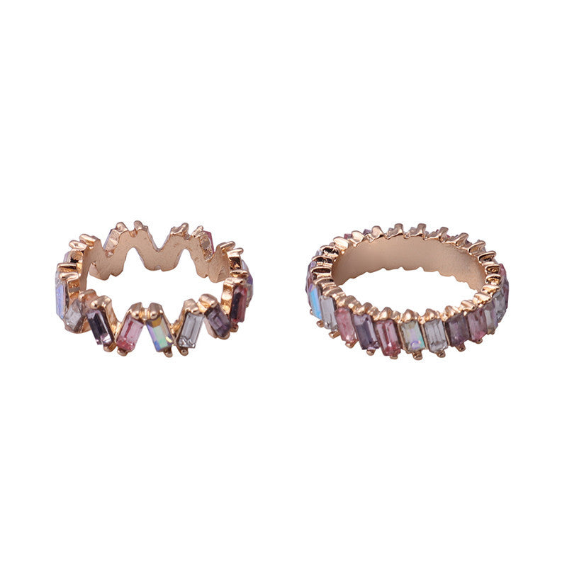 Pair of rose gold hoop earrings with multicolored gemstones on a white background