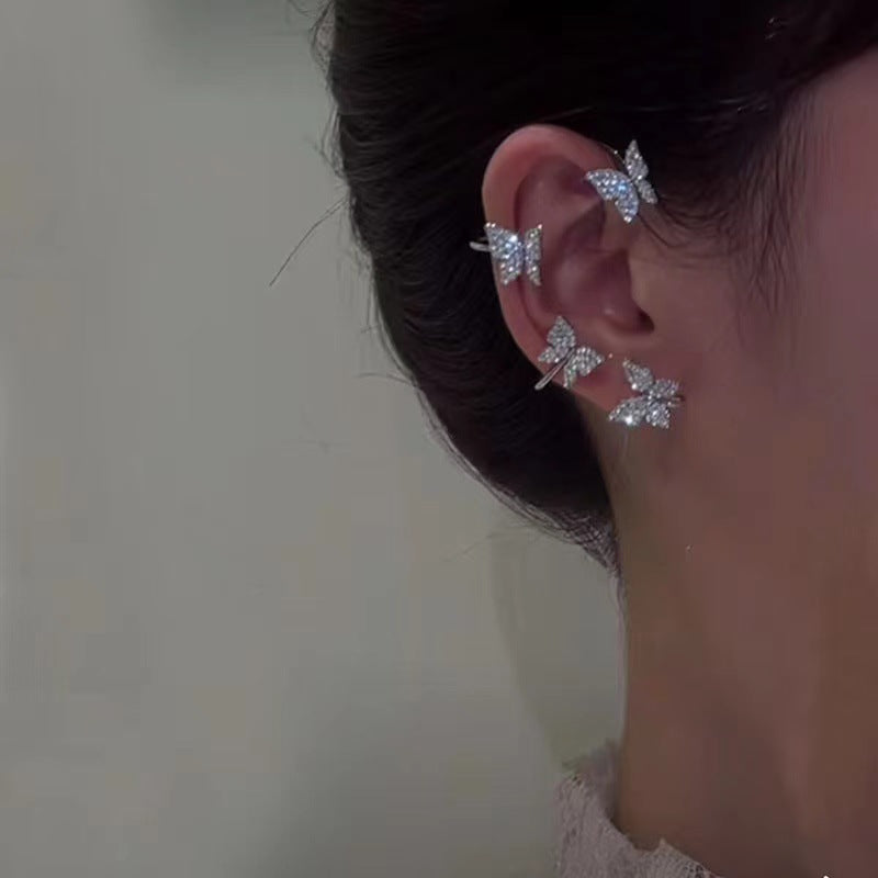 Close-up of an ear wearing a butterfly-shaped earring with a blurred background