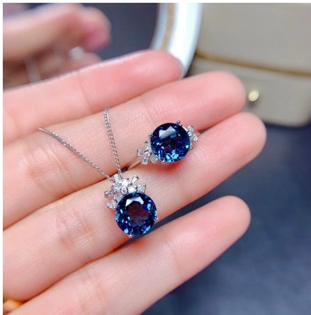Blue gemstone necklace and ring on a hand with blurred background