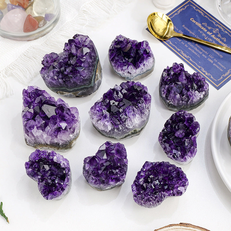 Collection of purple amethyst geodes on a white surface with a certificate of authenticity in the background.