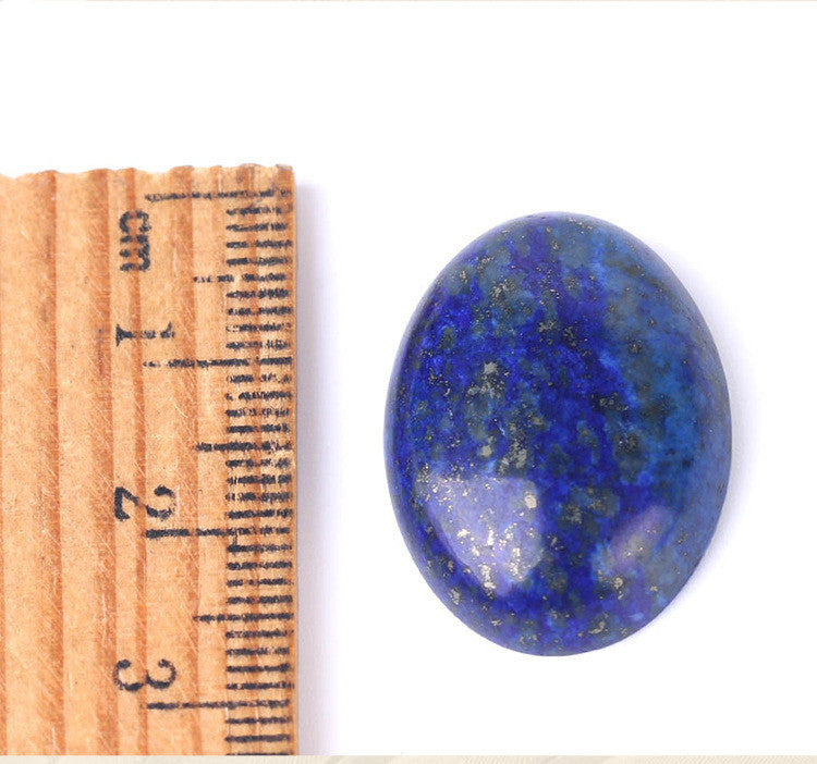 Blue stone next to a wooden ruler on a white background
