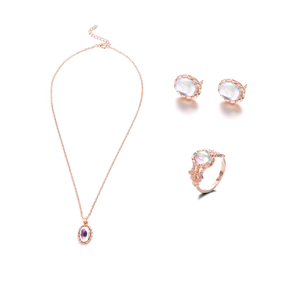 Rose gold jewelry set with necklace, ring, and earrings on a white background