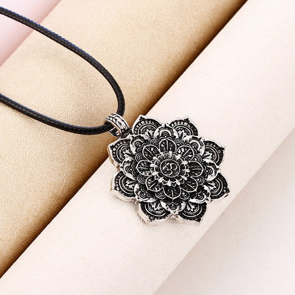 Black mandala pendant necklace on a beige background