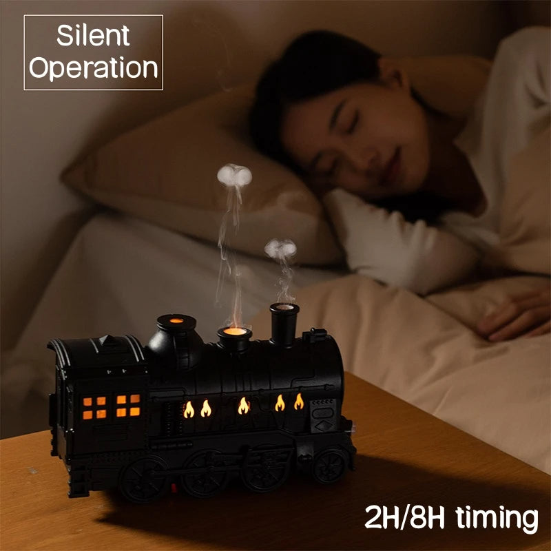 Black train-shaped night light on a bedside table with a person sleeping in the background.