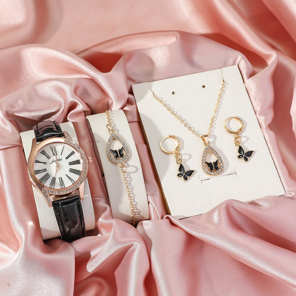 Jewelry set including a watch and necklaces on pink satin fabric