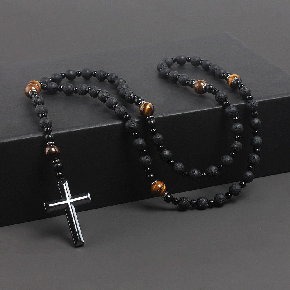 Black beaded necklace with a silver cross pendant on a dark surface