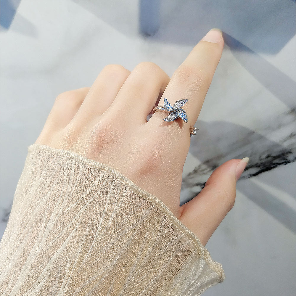 Hand wearing a silver ring with a butterfly design on a marble surface