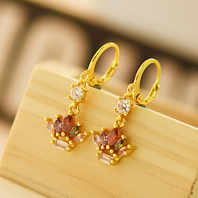 Gold earrings with gemstones on a wooden surface