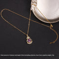 Gold necklace with a purple pendant on a black background