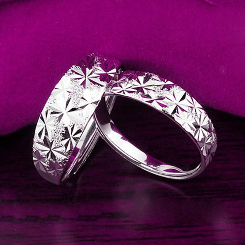 Silver ring with diamond-like patterns on a purple fabric background