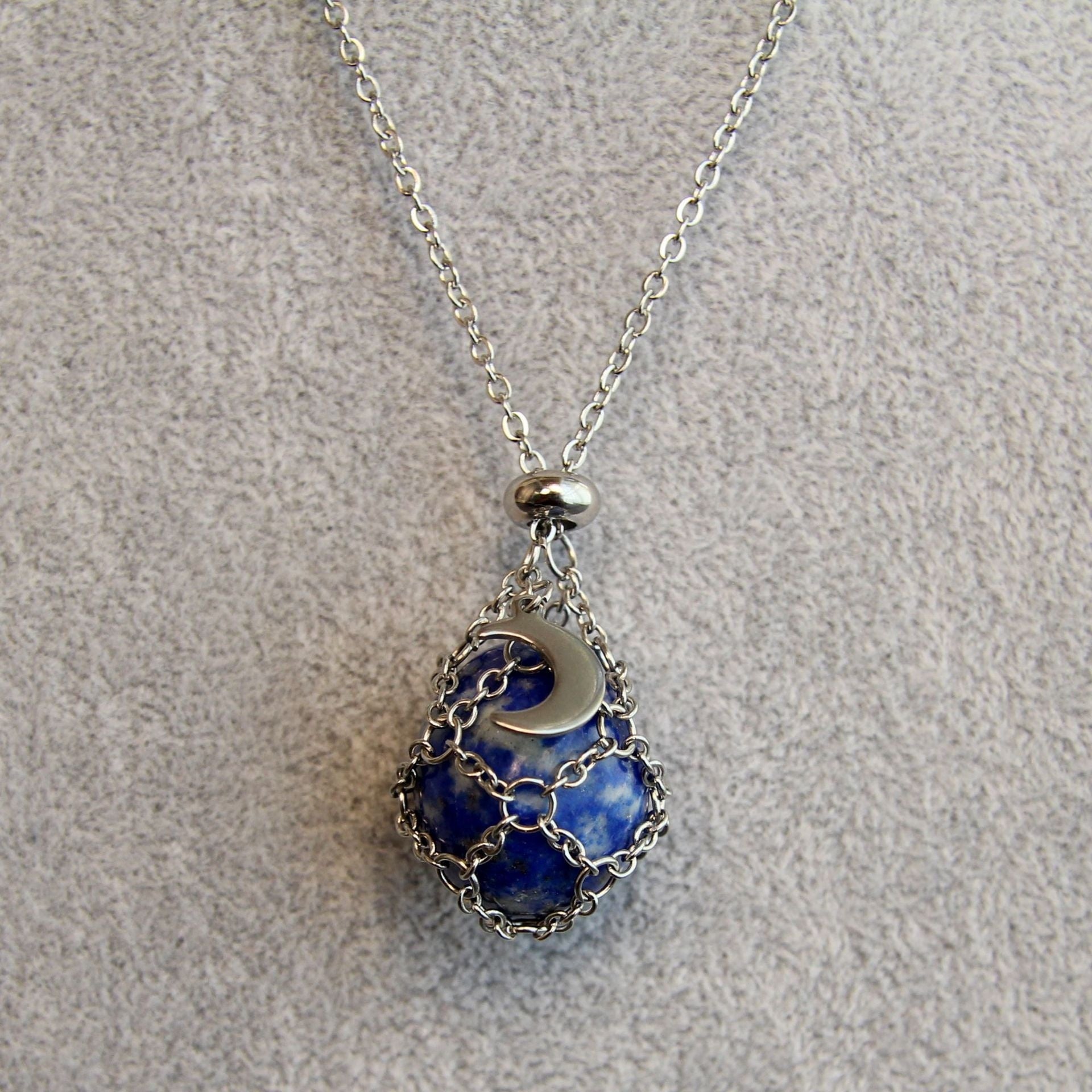 Necklace with a blue pendant and silver chain on a gray background
