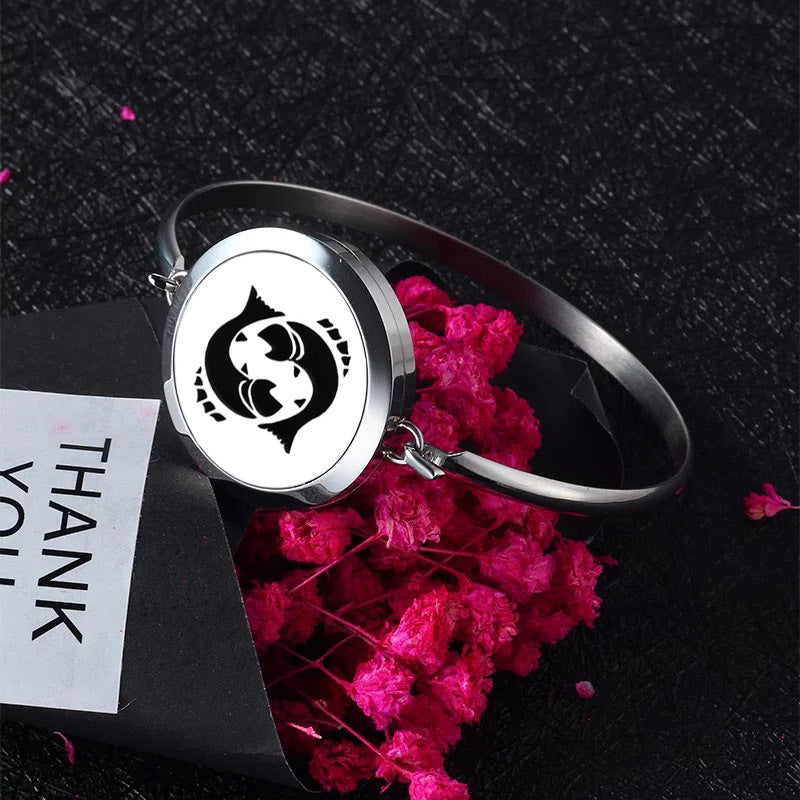 Silver bracelet with a black and white symbol on a dark background with pink flowers and a 'THANK YOU' card.