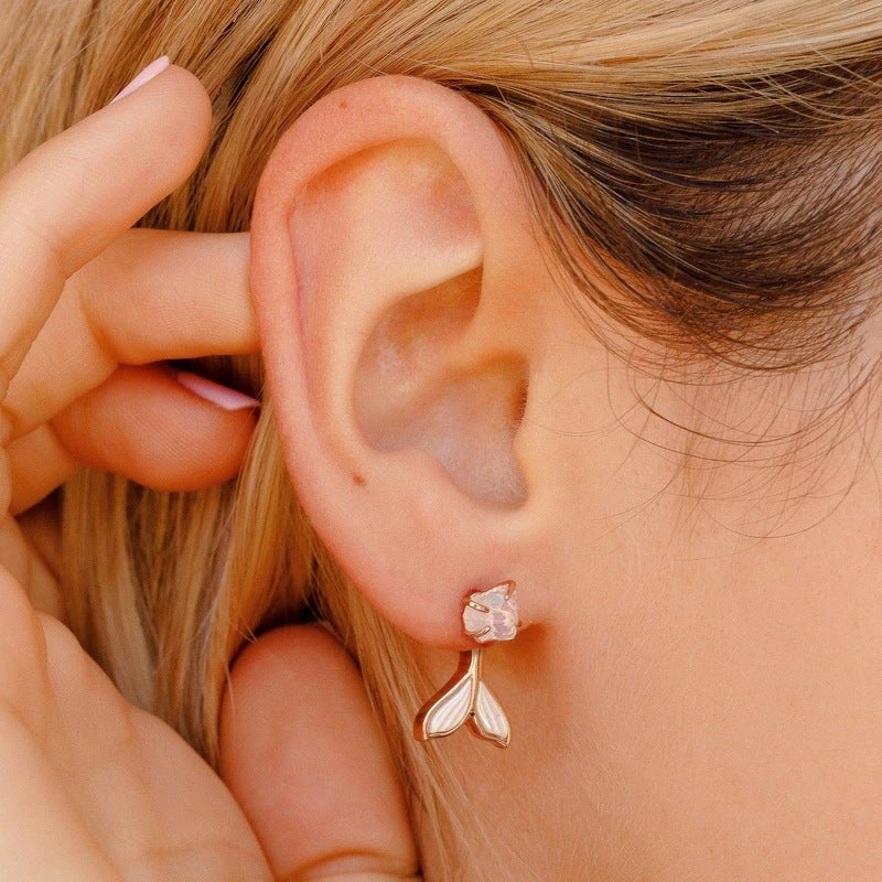 Close-up of an ear wearing a gold earring with a pink gemstone.