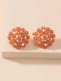 Pair of orange earrings with gemstones on a beige background
