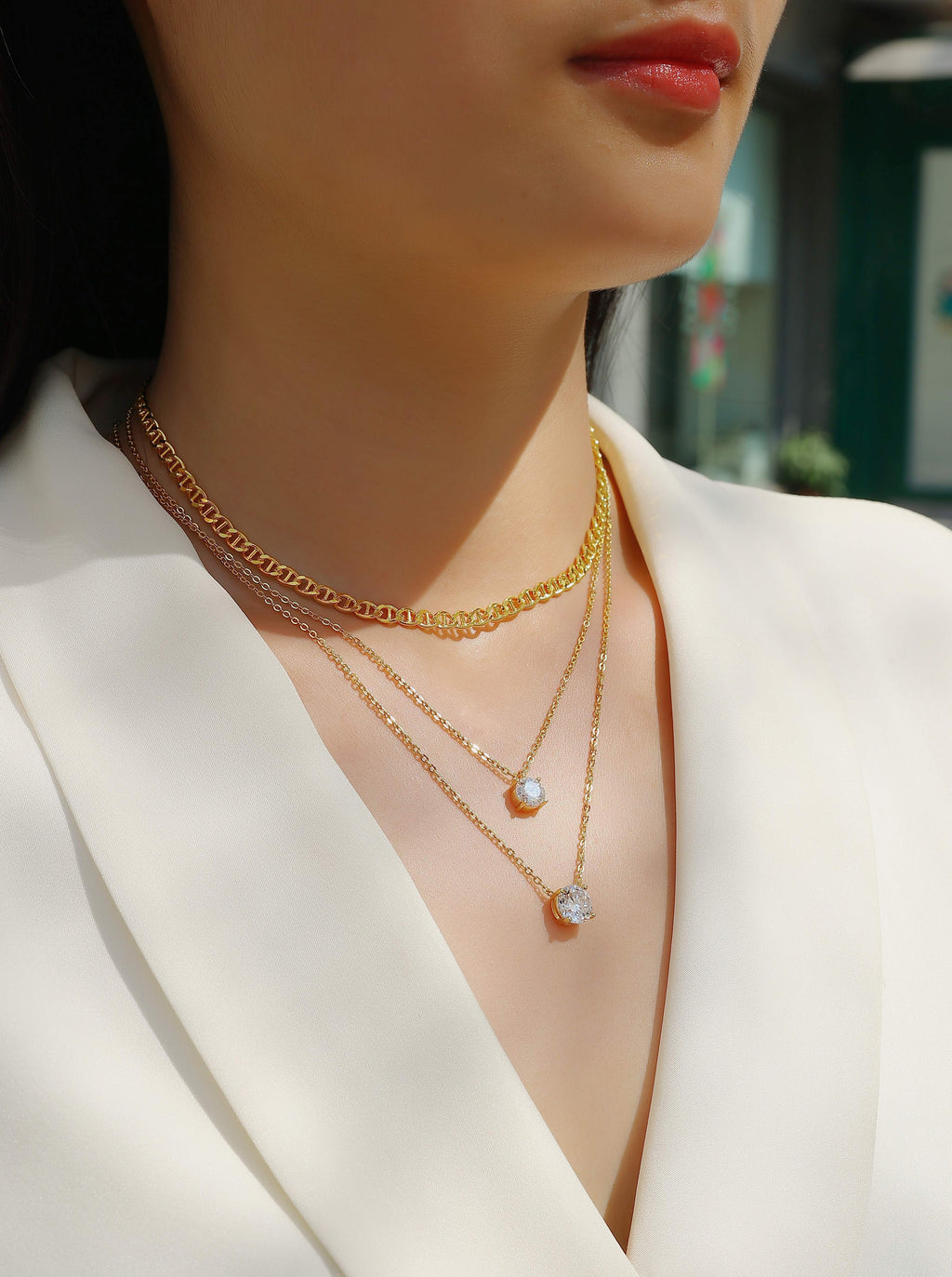 Close-up of a person wearing multiple gold necklaces with a blurred background