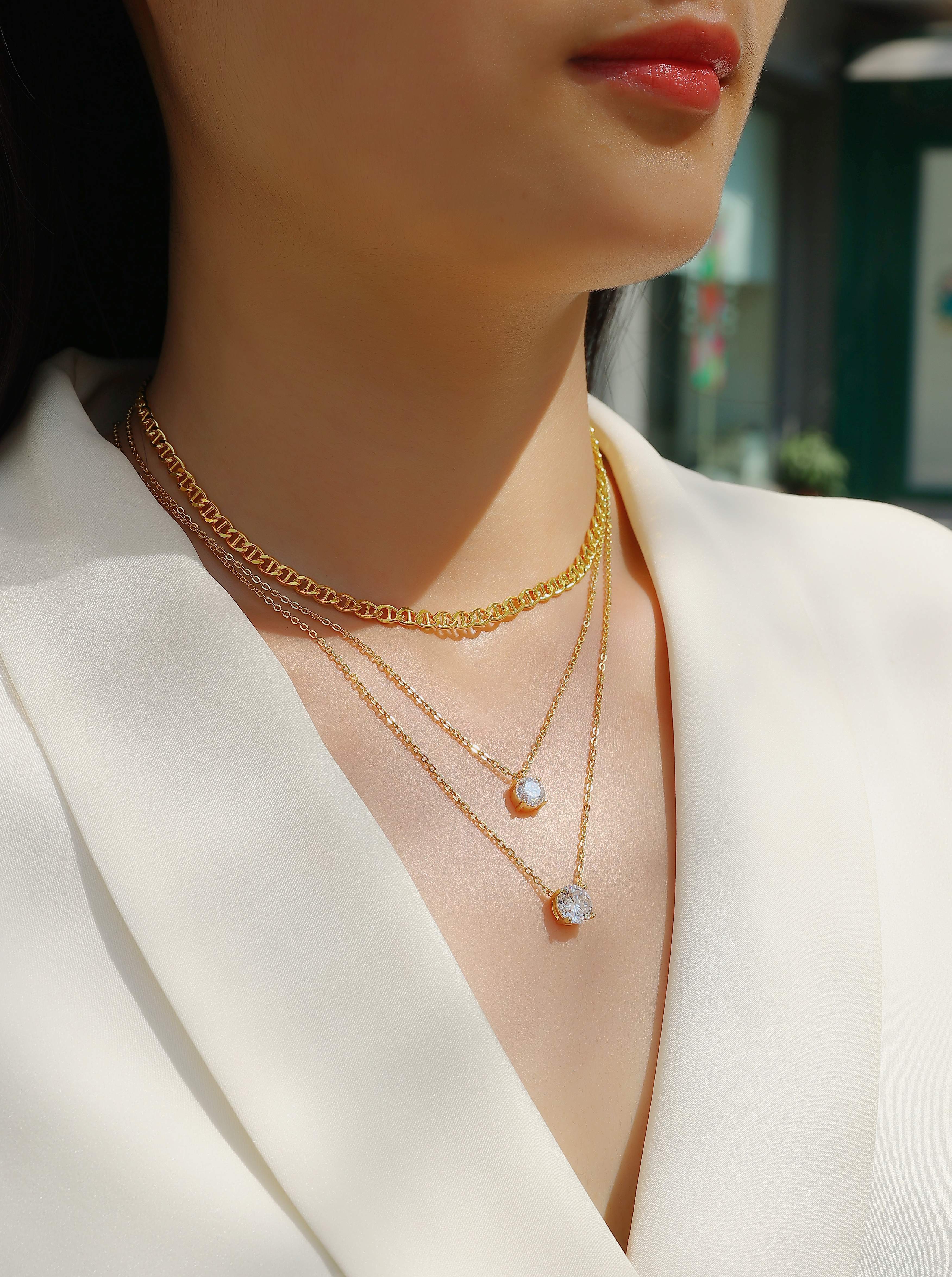 Close-up of a person wearing multiple gold necklaces with a blurred background