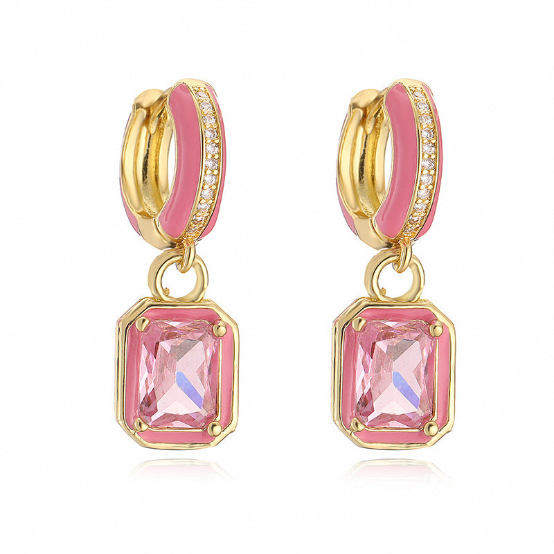 Gold hoop earrings with pink gemstones on a white background