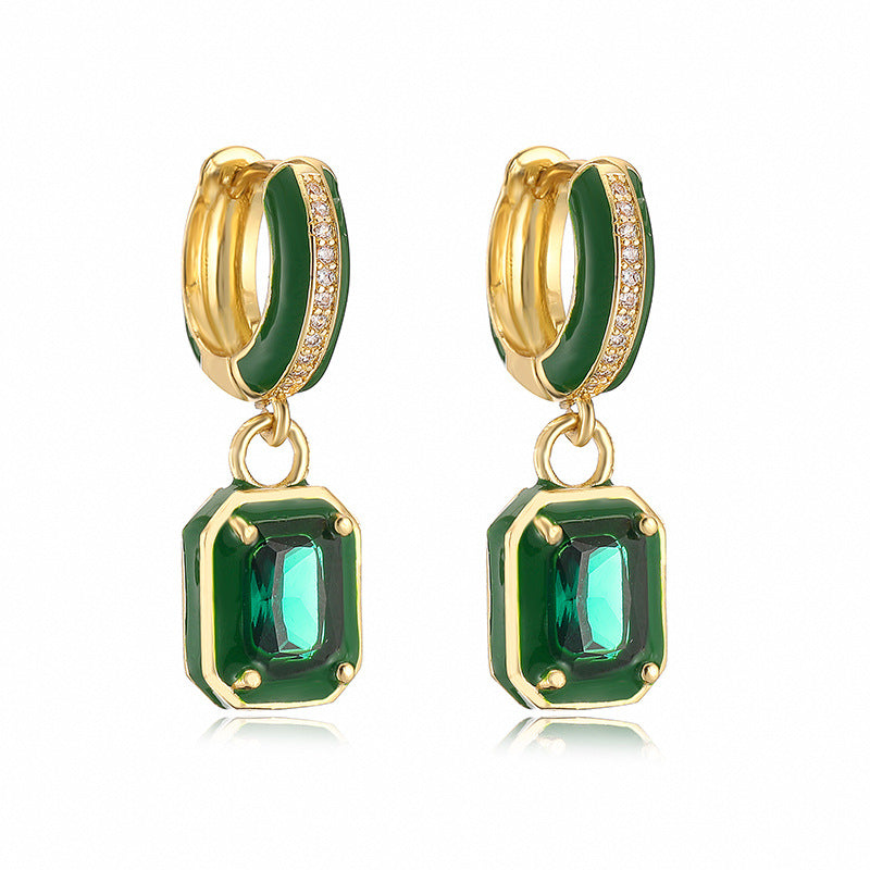 Gold hoop earrings with green gemstones on a white background