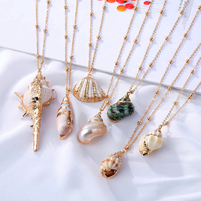 Gold chain necklaces with shell pendants on a white surface