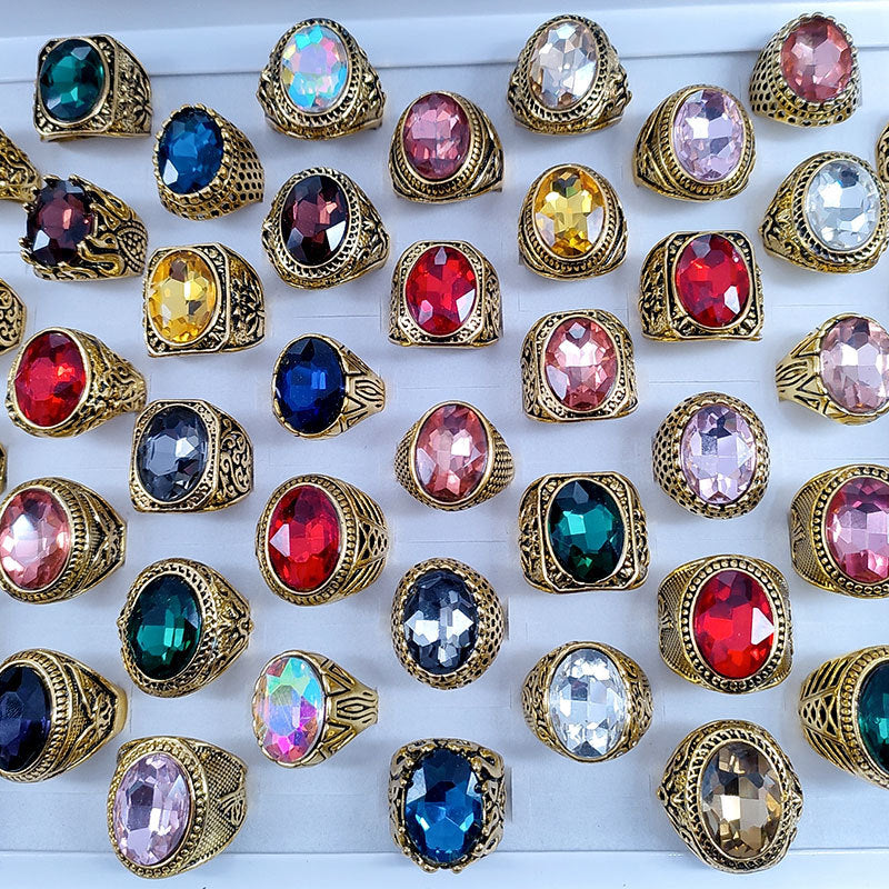 Collection of colorful gemstone rings with gold bands on a white background