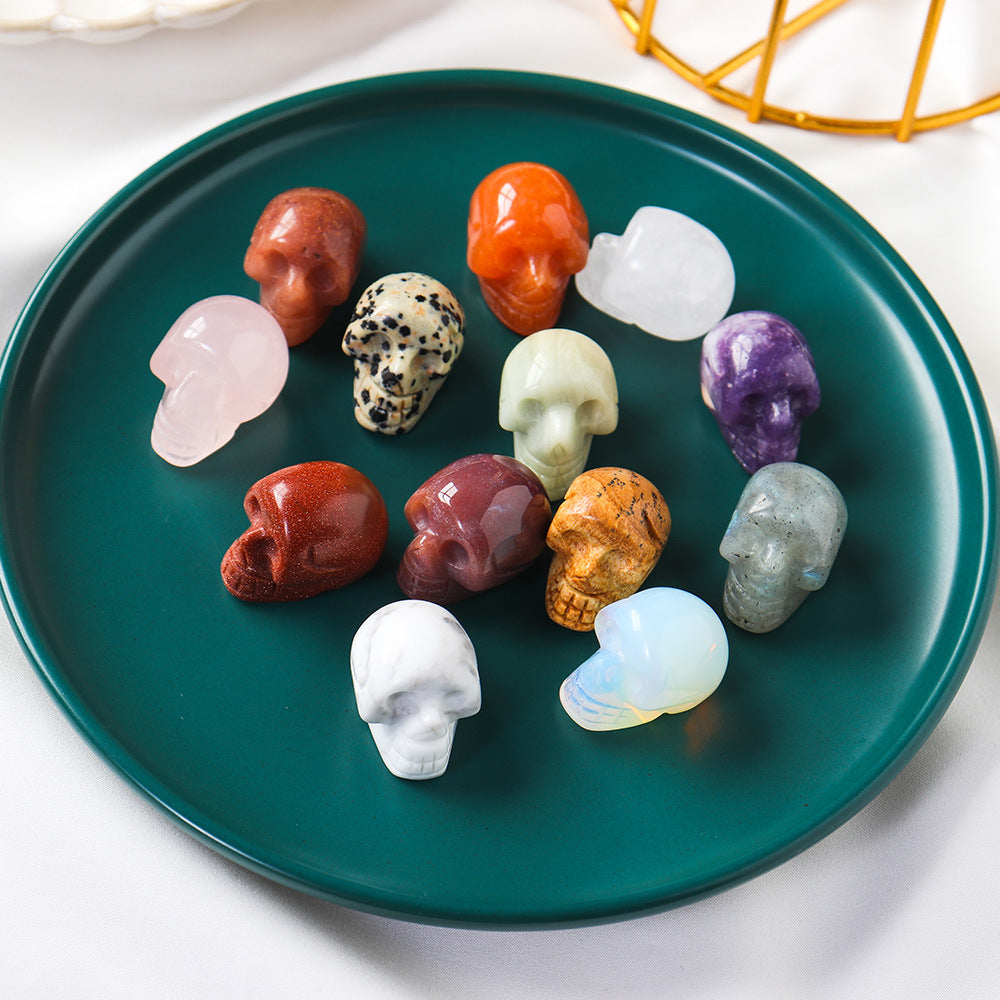 Assorted crystal skulls on a teal plate with a white background