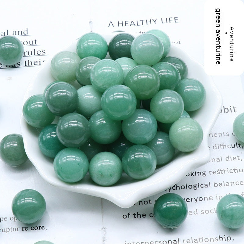 Green aventurine gemstones in a white bowl on a magazine page.